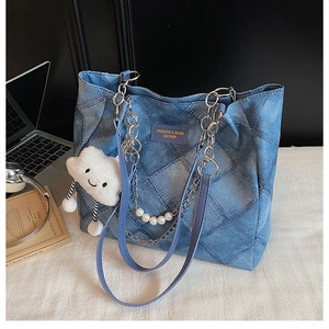 Details der blauen gesteppten Denim-Tasche mit lila Lederriemen und Perlenketten-Griff