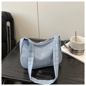 Detail of light blue denim shoulder bag with colorful bow prints and zipper closure