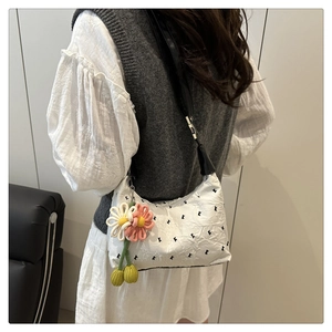 Detailed shot of white shoulder bag with floral crochet charms and black strap