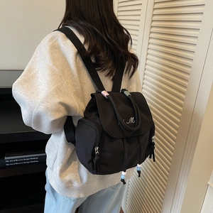 Minimalist black backpack with white M embroidery and colorful bead drawstring detail