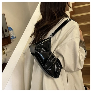 Detailed view of black patent leather shoulder bag with vintage metal buckle accent