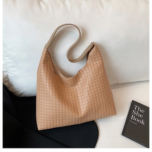 Detail of the woven texture and smooth shoulder strap on a khaki hobo tote bag