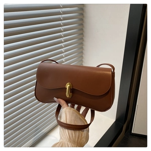 Detail view of vintage brown leather underarm bag with gold metal twist lock