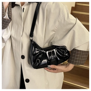Macro detail of glossy black faux leather surface and silver buckles on shoulder bag