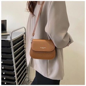 Dettaglio della borsa a sella marrone con trama intrecciata e scritta Fashion Trend