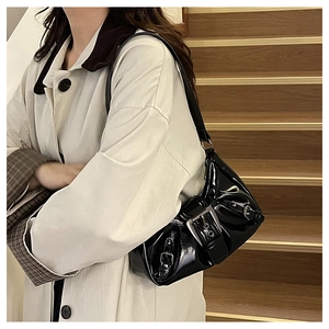 Detail of black patent leather underarm bag with silver buckle and pleated texture