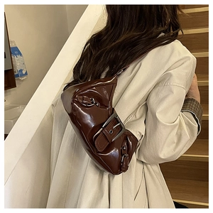 Detail of dark brown glossy shoulder bag featuring a prominent silver metallic buckle