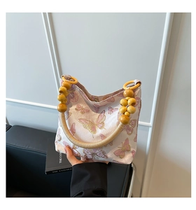 Detail of pink shoulder bag with colorful butterfly embroidery and wooden bead handle