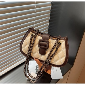 Detail of beige quilted shoulder bag with dark brown leather buckle and woven chain straps