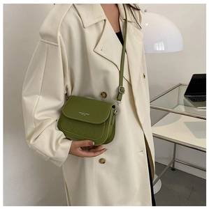 Dettaglio della borsa a sella verde con trapuntatura a rombi e scritta Fashion Trend