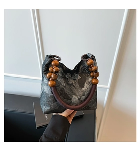 Close-up of retro butterfly print handbag with unique wooden bead handle and ring detail