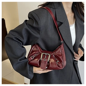 Detail of burgundy patent leather underarm bag with metal buckle and vintage pleats