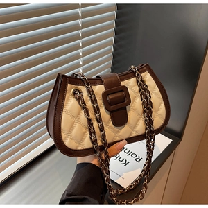 Detail of quilted beige PU leather bag with brown buckle and metal chain strap