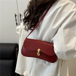 Retro burgundy shoulder bag with wave-shaped flap and gold oval buckle on white shirt