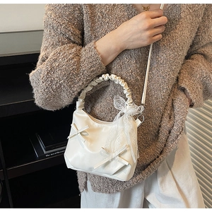 Detail view of white bucket bag with leather bow decoration and lace ribbons