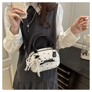 Detail of white pleated bag with black bow embroidery and large pearl lace charm