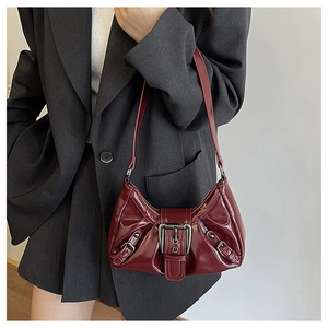 Close-up of a burgundy patent leather hobo bag with silver buckle and glossy finish