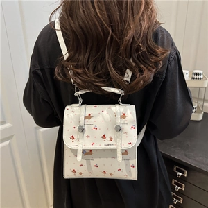 Mini sac à dos blanc avec motifs chiots et cerises, porté par un mannequin à domicile
