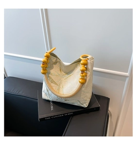 Detail of fabric bucket bag with leaf pattern and unique mustard wood bead handle
