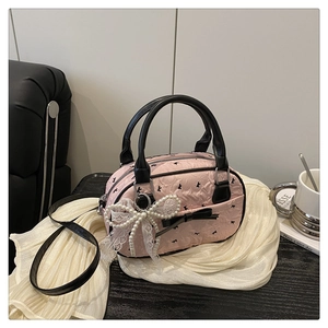 Detailed view of pink Boston bag with black bow prints and pearl lace bow charm