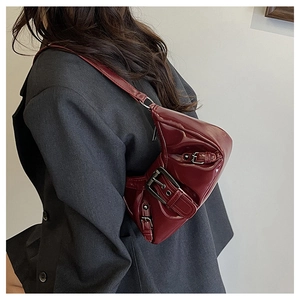 Detail of burgundy patent leather underarm bag with silver buckles on shoulder model