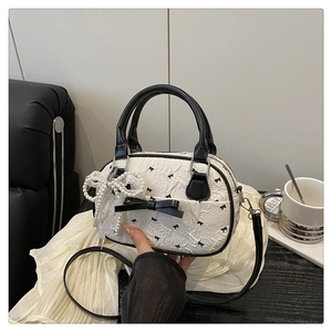 Detail of white pleated handbag with black bow and elegant pearl lace pendant