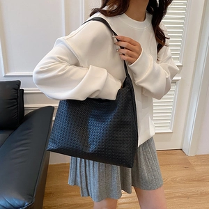 Chic black woven leather tote bag for women showing a minimalist hobo style design
