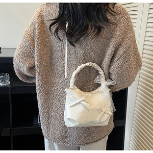Detail of white PU leather bucket bag with ribbon bows and pleated handle on shoulder