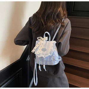 Close-up of blue plaid mini backpack with white lace bow and ruffled edge details
