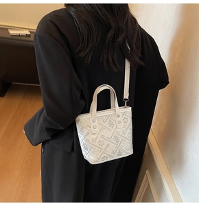 Detailed close-up of white embossed tote bag with geometric patterns and shoulder strap