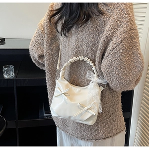 Detailed close-up of cream leather bucket bag with 3D bows and white lace ribbon