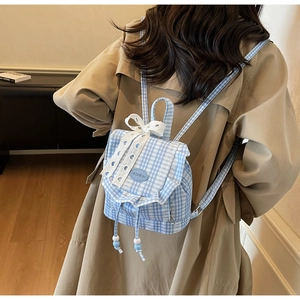 Detailed view of the blue and white plaid backpack with white lace and bow accents