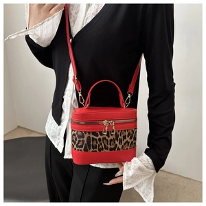 Detail of red and leopard print mini bucket bag with gold zippers and leather strap