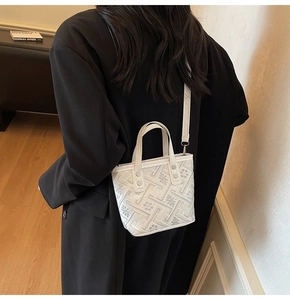Detail of cream bucket bag featuring intricate floral embroidery and adjustable strap