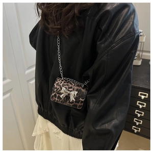 Close-up of leopard print crossbody bag with silver metal bow and delicate chain strap