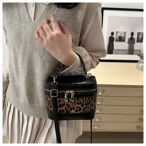 Close-up of leopard print cylinder bucket bag with gold zippers and leather strap