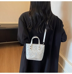 Detail of white mini bucket bag with geometric jacquard pattern and silver straps