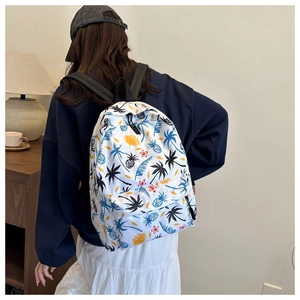 Rear view of a stylish backpack with tropical palm and floral prints in a home setting