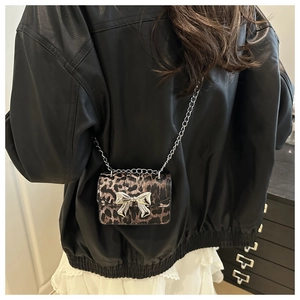 Detail shot of a mini leopard print crossbody bag with silver bow on a black leather jacket