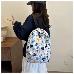 Detail of tropical pineapple and palm leaf print on white nylon backpack with zippers