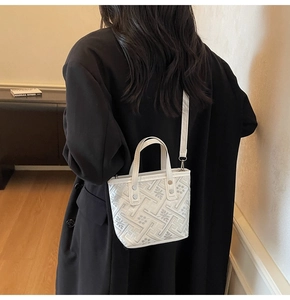 Detail of white textured mini bucket bag with geometric patterns and silver studs
