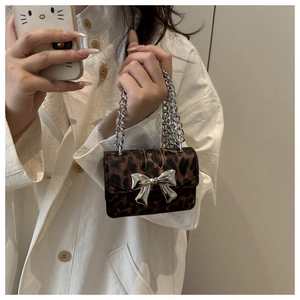 Detail of leopard print mini handbag featuring silver metal bow and dual chain straps
