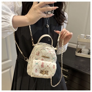 Detail of mini crossbody bag featuring pink cartoon prints and gold fashion plaque