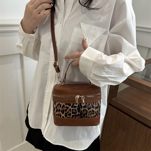 Brown leather cylinder bucket bag with leopard print stitching and adjustable strap