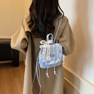 Blue and white plaid mini backpack with lace bow and drawstring tassels shown on a model