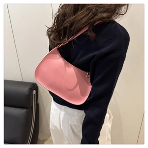 Pink minimalist crescent shoulder bag with leather texture shown on model's shoulder