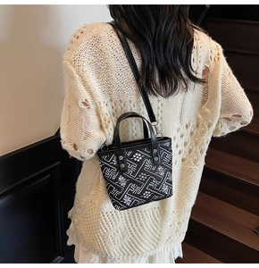 Rear view of model wearing a black bucket bag with white floral geometric patterns