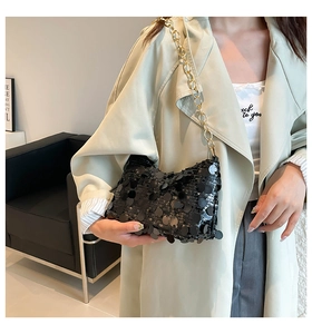 Close-up of black sequins and golden metal chain strap on a stylish shoulder bag