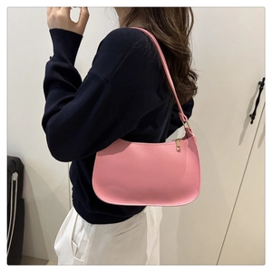 Detail of pink half-moon underarm bag in textured leather with golden zipper on a model