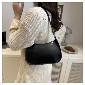 Detail of a black half-moon hobo bag with gold zipper and smooth leather finish